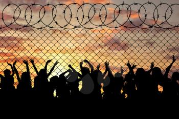 Concept of the refugees. Silhouette of a crowd of refugees at the border at sunset
