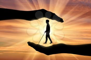 Association of blind people with disabilities under protection in hands sunset. Concept help blind people disabilities