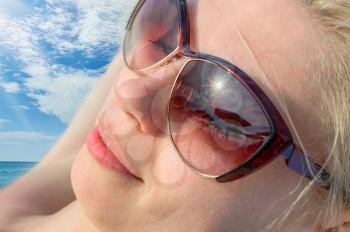 Young woman resting at beach in sunglasses. tourism and recreation concept