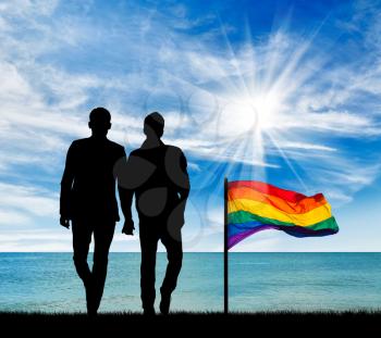 Concept of gay people. Silhouette of two gay men on a walk by the sea during the day and a rainbow flag