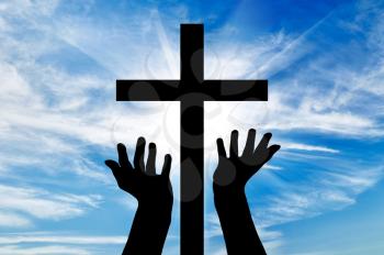 Concept of religion. Silhouette of hands outstretched on the cross against a beautiful sky