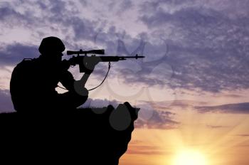 Silhouette of a soldier sniper on top at sunset