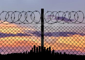 concept of security. Silhouette of barbed wire fence on the background of the city away