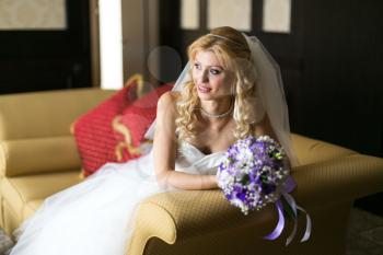 Wedding concept feelings and emotions. Beautiful and elegant bride smiling with a bouquet of flowers in the room sitting