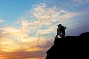 Loneliness concept. Silhouette of a woman alone on a hill at sunset
