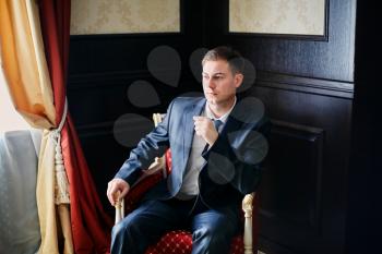 Concept of success in business. Successful young businessman sitting in an armchair and thinking