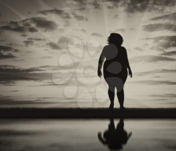 Fat woman standing near water and reflection background of sky. Concept obesity