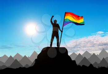 Silhouette with the gay rainbow flag on a mountain top. Concept rights and freedoms of gays