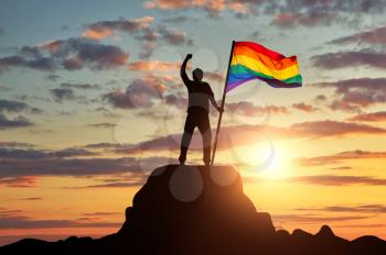 Silhouette with the gay rainbow flag on a mountain top. Concept rights and freedoms of gays