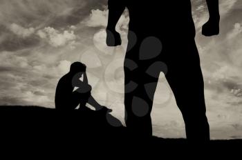 Child abuse and bullying in the family. Silhouette of a crying frightened boy and aggressive father with fists