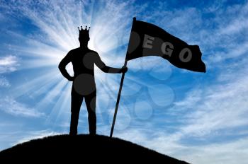 Silhouette of a selfish man with a crown on his head holds a flag with the word ego on top of a hill. The concept of selfishness and narcissism