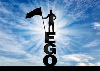 Silhouette of a selfish man who holds a flag on top of the word ego. The concept of selfishness and narcissism