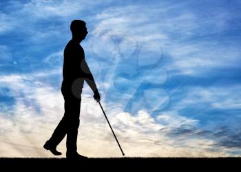 Silhouettes of a blind disabled man with a cane in his hand walking against the sky. The concept of blind people with disabilities