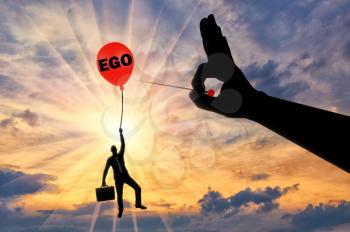 A selfish businessman clings to a balloon called the ego and a big hand with a needle intends to burst it. Conceptual Scene