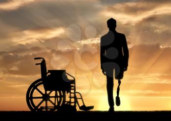 Disability and rehabilitation. Walking is a disabled man with a prosthetic leg and a wheelchair at sunset