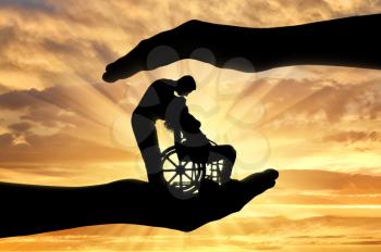 Silhouettes of a happy disabled woman in a wheelchair with a man who kisses her. The concept of support and assistance for people with disabilities