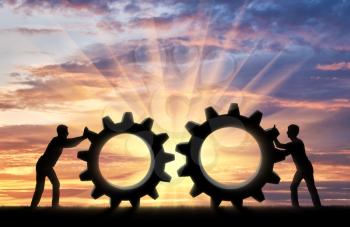 Silhouette of two people who want to connect the two gears in a single mechanism. Business team concept