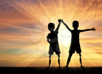 Children with disabilities. Two boys of a disabled person with a prosthetic leg standing, holding hands on sunset background