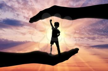 Help children with disabilities concept. Happy disabled boy with a prosthetic leg standing in the helping hands at sunset