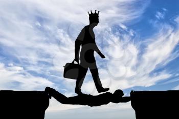 Selfish man with a crown on his head is walking over a man in the form of a bridge over an abyss. Concept of selfishness in business