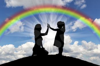 Silhouette, little happy girl child with mom on the hill and rainbow in the sky. Conceptual image