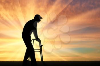 Silhouette of a disabled man walking, using a walker for the disabled. The concept of the elderly and disabled