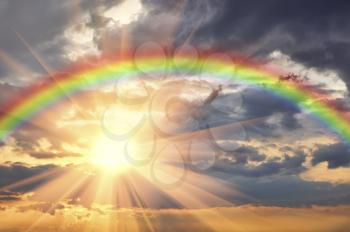 Rainbow in the beautiful sky at sunset and the bright sun with rays