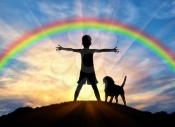 Happy childhood concept. Silhouette of a happy child and dog on top of a hill on rainbow background