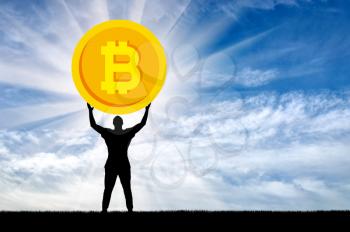 Silhouette of a man holding a coin bitcoin against the sky. The concept of the future for crypto currency