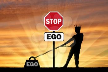 The silhouette of a selfish man with a crown on his head draws a heavy load - the ego and the stop sign of the ego. Conceptual scene of selfishness