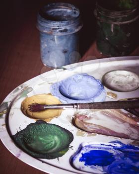 Palette with paints and a brush. Photo toned.
