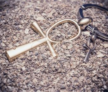 Large and small Egyptian ankh cross in the sand. Photo toned.