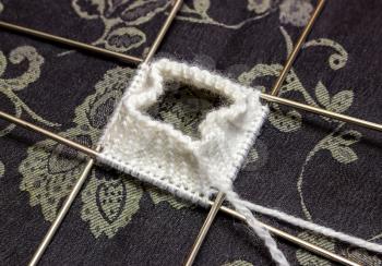 Knitting white mitts on five spokes - a work in progress.
