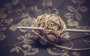 A ball of linen yarn and a crochet hook. Photo toned.