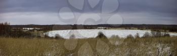 Winter panorama with blue clouds and snow-covered field.