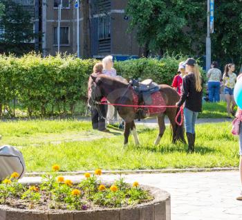 Udomlya, Russia - June 1, 2016: Ponies, women and children on International Children's Day.