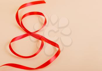 Red gift celebration ribbon in 8 digit shape on paper. Happy woman's day, eight of march