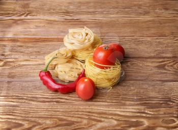 Pasta spaghetti noodles with chili pepper and tomatoes on wooden table