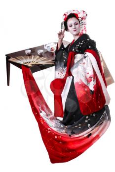 young pretty geisha in kimono with sakura and decoration. Portrait of a Japanese geisha woman with table with the tea ceremony isolated on white