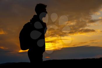 Silhouettes of hiker with backpack enjoying sunset view from top of a mountain. Winner silhouette on the mountain top. Sport and active life concept