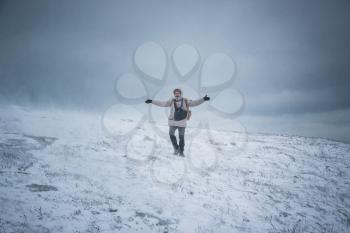 Wintery scene of shivering man in snowstorm or ice storm. Man walking in the snowstorm in the mountains