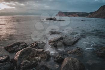 Long exposure of sea and rocks. Wispy Sunset taken with long shutter speed to show motion blur