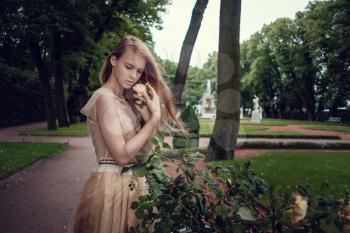 A young red-haired girl in a delicate peach dress is walking along a beautiful old town. St.Petersburg