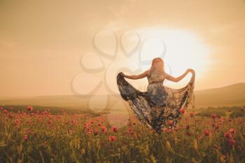 Young beautiful woman in spring field. concept of freedom. walking in amazing poppy field. Warm sunset colors. Soft colors.