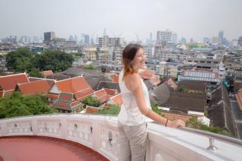 Girl admires the view from the Golden Mount, Thailand. Bangkok City panorama with skyscrapers of business district from Golden Mountain Wat Saket roof