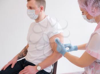FEMale doctor holding syringe making covid 19 vaccination injection dose in shoulder of male patient. Flu influenza vaccine clinical trials concept, corona virus treatment side effect, close up view.