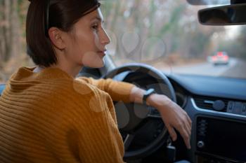 Rear view of an attractive young asian woman in casual clothes looking over her shoulder while driving