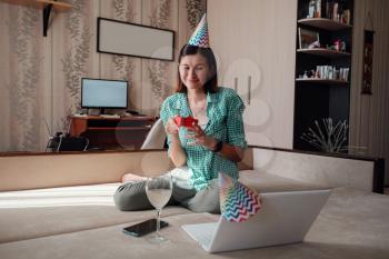 woman celebrating birthday online in quarantine time through video call virtual party. Coronavirus outbreak 2020. Woman opening a gift and have positive emotions.