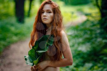 Protection of the environment, rescue of plants and nature. A young ginger woman stand in the green fairy forest. Idea and concept of Arbor day or Mother earth day