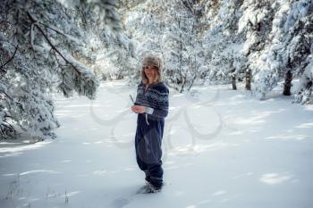 beautiful girl standing, in winter in forest park, background of Christmas tree snow, she is resting in resort. Free space for text. Blue jumpsuit for sports.